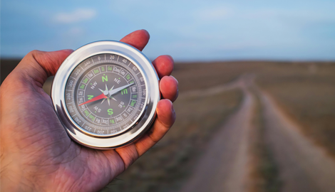 man holding a compass at a cross road